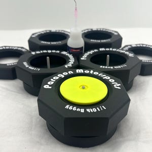May include: Six black hexagonal bottle stoppers with the text "Paragon Motorsports" and "11014 Buggy" printed in white. A small bottle of glue is in the center of the image.