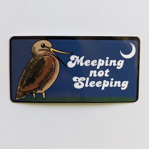 May include: A blue and green sticker with a cartoon bird and the text "Meeping not Sleeping" in white letters. A crescent moon is in the upper right corner.