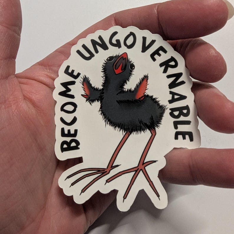 May include: A white sticker featuring a cartoon bird with black plumage, red wings and legs. The sticker has the text "I BECOME UNGOVERNABLE" in a semi-circular design around the bird. The bird has long, thin legs.
