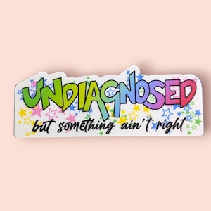 May include: A sticker with the word "UNDIAGNOSED" in colorful bubble letters, with the phrase "but something ain't right" below. The sticker is white with a star pattern.