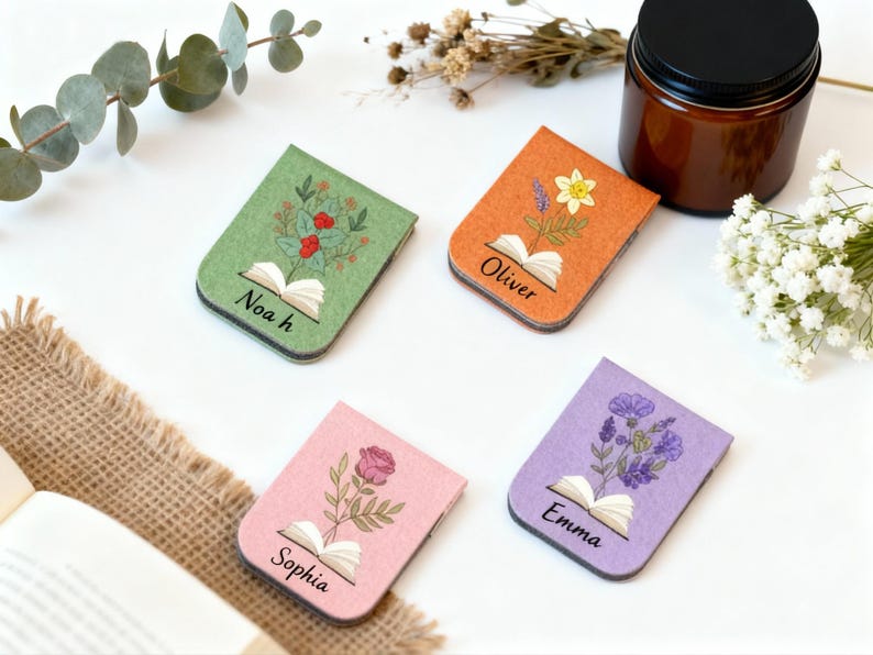 May include: Four felt bookmarks in green, orange, pink, and purple, each with a floral design and a name: Noah, Oliver, Sophia, and Emma. Each bookmark features an open book illustration. Ideal for book lovers.