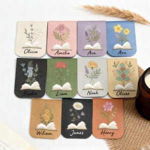 May include: A set of floral bookmarks, each with a different flower design and a name such as Olivia or Amelia. The bookmarks are in various colours, including beige, pink, and blue. Each design includes an open book.