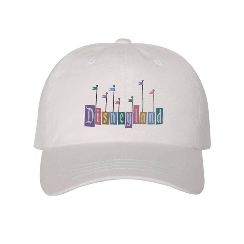 Pu&ograve; includere: Cappellino da baseball bianco con un logo Disneyland colorato con bandiere e il testo "Disneyland".