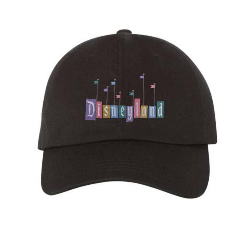 Pu&ograve; includere: Cappellino da baseball nero con un logo Disneyland colorato con bandiere e il testo "Disneyland" in un font vintage.
