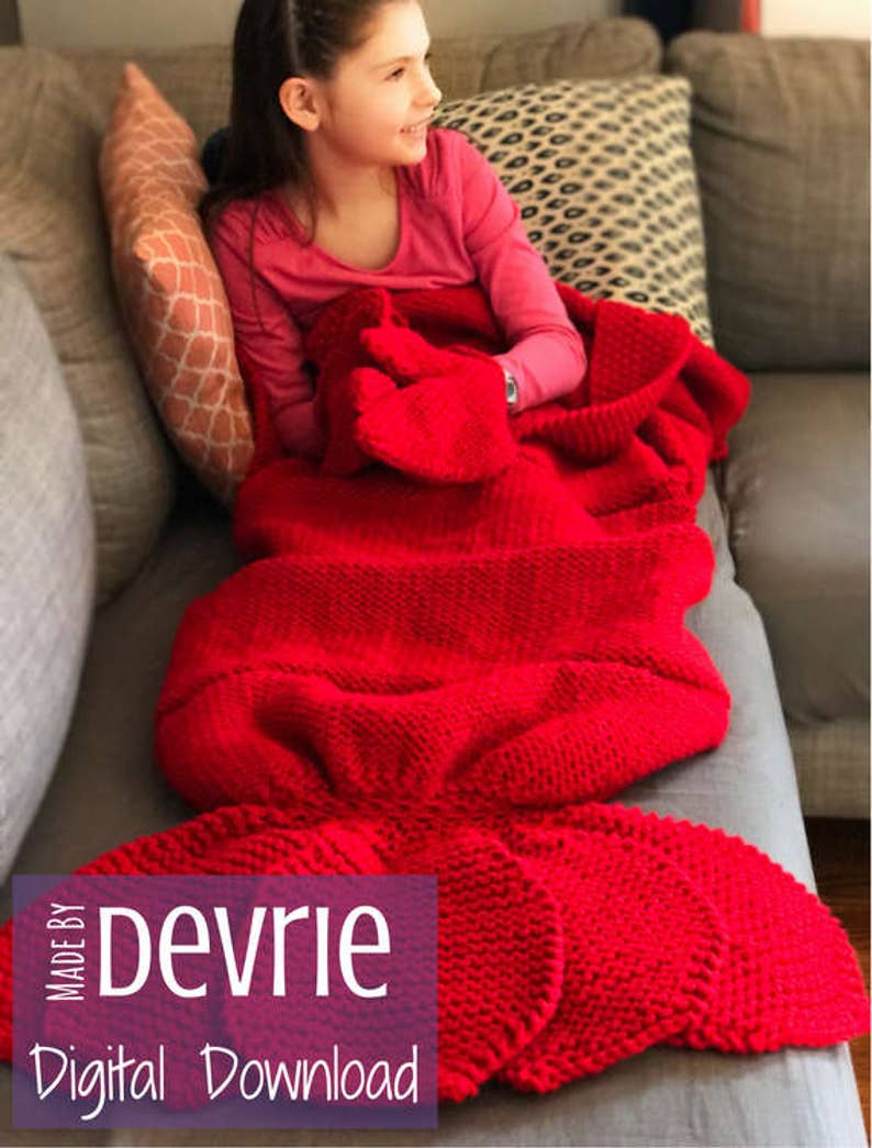 May include: A red knitted mermaid tail blanket with a girl sitting on a couch. The blanket has a large tail fin and a smaller fin on each side. The text "MADE BY Devrie Digital Download" is on the bottom left corner of the image.