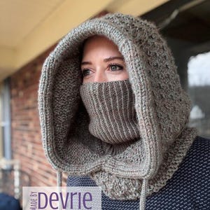 May include: A knitted hood in shades of gray and brown, featuring a textured pattern on the hood and a ribbed face covering. The hood is designed to cover the head and neck, with drawstrings for adjustment. The text "MADE BY Devrie Digital Download" is visible.