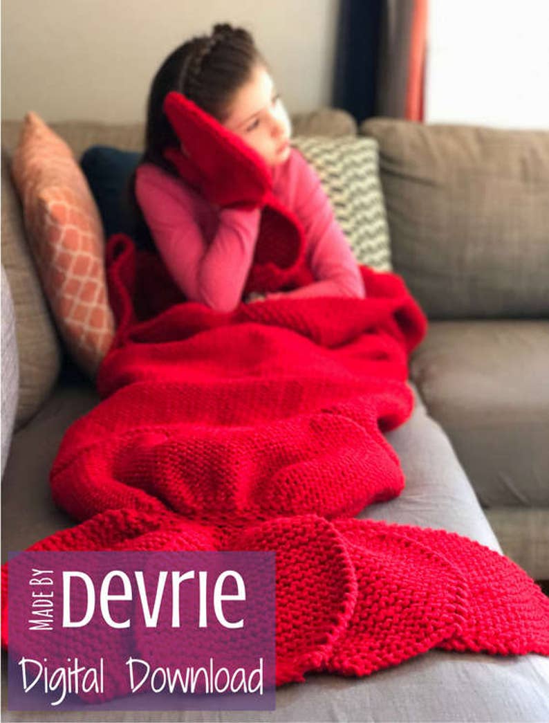 May include: A red knitted blanket with a mermaid tail design. The blanket is on a couch with a young girl sitting on it. The text "MADE BY Devrie Digital Download" is on the blanket.