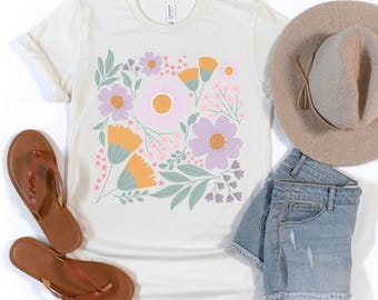 May include: A white t-shirt with a floral print featuring purple, pink, orange, and green flowers. The shirt has a crew neck and short sleeves.