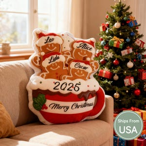 May include: A Christmas-themed pillow shaped like a mug filled with gingerbread people. The pillow has the text "2025" and "Merry Christmas". Each gingerbread person has a name: Leo, Lida, Alice, and Oscar. A Christmas tree is in the background.