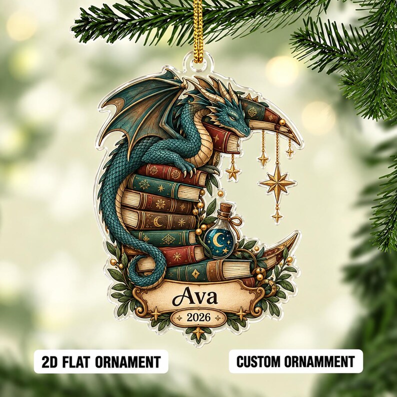 May include: A flat acrylic ornament featuring a teal dragon perched on a stack of colorful books shaped like a crescent moon. The design includes hanging gold stars, a small potion bottle, and a banner with the name Ava and the year 2026.