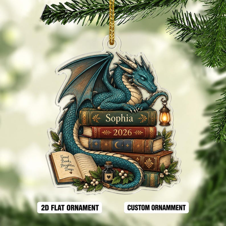 May include: A flat acrylic ornament featuring a teal dragon perched on a stack of books. The books are labeled with the name Sophia and the year 2026. An open book displays the text Good Books Brighter Days, accompanied by a small ink bottle.