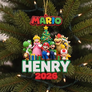 May include: A decorative Christmas ornament featuring Mario, Luigi, Princess Peach, Yoshi, Bowser, Toad, and a small dog. The ornament includes a central Christmas tree, the text MARIO at the top, and the name HENRY with the year 2026 at the bottom.