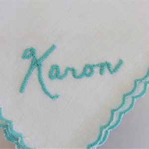 May include: White linen handkerchief with a turquoise blue embroidered border and the name "Karen" embroidered in turquoise blue script.