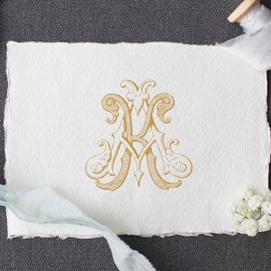 May include: A gold monogram with the letters "A" and "R" intertwined, on a white paper background. The monogram is surrounded by decorative flourishes.