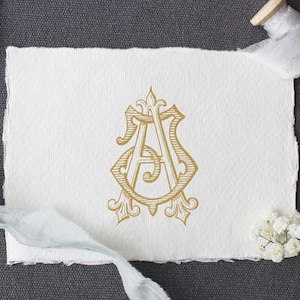 May include: A gold monogram with the letters "A" and "S" intertwined in a decorative design. The monogram is on a white piece of paper.