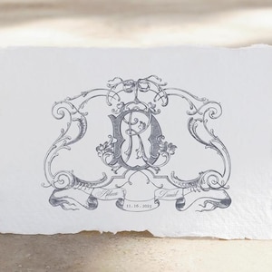 May include: A black and white wedding monogram with a decorative flourish design. The monogram features the letters "R" and "C" intertwined. The text "Rebecca" and "David" are on banners below the monogram, with the date "11.16.2025" underneath.