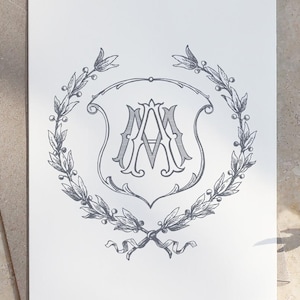 May include: A black and white monogram with the letters "AA" inside a shield shape, surrounded by a wreath of leaves.