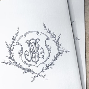 Puede incluir: Una tarjeta blanca con un monograma gris en un diseño de corona. El monograma es una "M" y una "S" estilizadas entrelazadas.