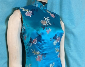 May include: A sleeveless blue silk cheongsam dress with a mandarin collar and a floral pattern. The dress has a gradient from a darker blue at the top to a lighter blue at the bottom.