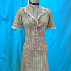 May include: A vintage two-piece dress with a striped pattern in shades of brown, green, and white. The dress has a fitted bodice with a button-up front and a full skirt. The bodice features a lace trim around the collar.