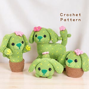 May include: Four crocheted cactus dog plushies in different sizes. The plushies are green with yellow accents and pink flowers. The plushies are sitting on a light wood surface. Crochet Pattern.