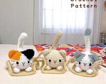 May include: Three crocheted cat figurines, each with a different color pattern, sitting on a crocheted bed. The cats are white with orange, white with beige, and white with gray. The text "Crochet Pattern" is visible in the image.