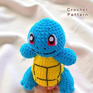 May include: A handmade blue and yellow crochet Squirtle plush toy. The plush has a blue head, arms, and legs, with a yellow shell. The eyes are white with red accents. The text "Crochet Pattern" is visible.