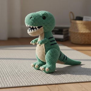 Könnte beinhalten: Ein gehäkeltes Tyrannosaurus Rex Dinosaurier-Spielzeug in Grün- und Beigetönen. Der Dinosaurier hat ein weit geöffnetes Maul mit weißen Zähnen, kleine Arme und einen langen Schwanz. Dunkelblaue Streifen akzentuieren den Rücken und den Schwanz. Das Spielzeug steht auf einem hellgrauen Teppich.