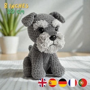 Puede incluir: Un perro de ganchillo gris y blanco hecho a mano, de 20 cm de altura, con barba y cejas esponjosas. El perro tiene ojos negros y nariz negra. El texto "8 inches 20 cm" está encima del perro.