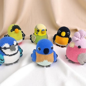 以下が含まれることがあります： 様々な色の手作りの鳥の編みぐるみ6羽のコレクション。青、黄色、緑、黒、ピンクの鳥で、翼とくちばしが詳細に表現されています。各鳥は約8〜10cmの高さで、家の装飾や子供のおもちゃに最適です。