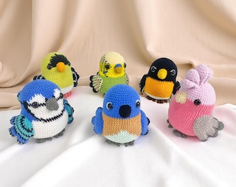 May include: A collection of six handmade crochet bird figurines in various colors. The birds include blue, yellow, green, black, and pink, with detailed wings and beaks. Each bird is approximately 3-4 inches tall, perfect for home decor or children's toys.