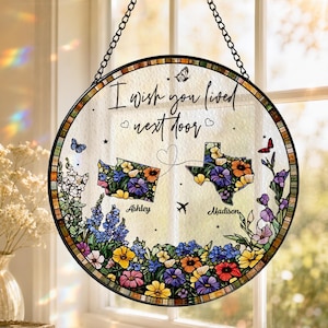 Könnte beinhalten: Ein runder Sonnenfänger aus Buntglas mit dem Text I wish you lived next door, zwei blumengefüllten Landkarten von Washington und Texas, den Namen Ashley und Madison, einem Flugzeugsymbol und Schmetterlingen, aufgehängt an einer schwarzen Kette.