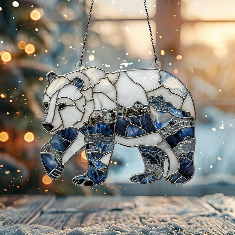 May include: A stained glass window hanging ornament featuring a white bear with blue and silver accents. The bear is walking with its head turned to the side.