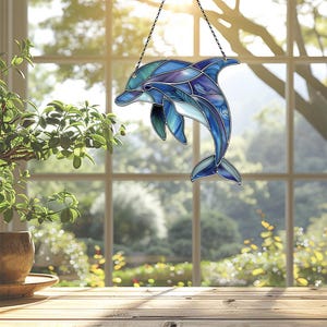 Puede incluir: Una ventana colgante de vitral con un delf&iacute;n azul con acentos morados y verdes. El delf&iacute;n est&aacute; saltando fuera del agua.
