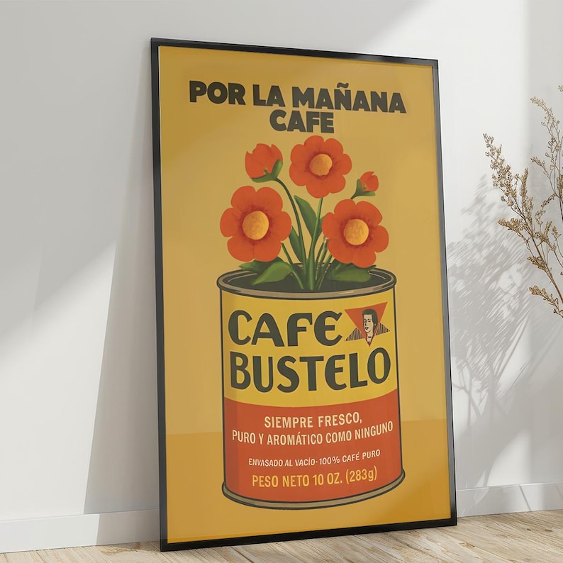 Pode incluir: Um poster emoldurado com fundo amarelo apresenta um design de lata de caf&eacute; com o texto "CAFE BUSTELO". A lata cont&eacute;m flores laranja. O texto superior diz "POR LA MA&Ntilde;ANA CAFE". O texto inferior diz "PESO NETO 283g (10 oz)."