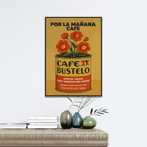 Pode incluir: Um cartaz vintage emoldurado para Cafe Bustelo, apresentando uma lata de caf&eacute; com o nome da marca e texto em espanhol. O cartaz tem um fundo amarelo com flores laranja e o texto "POR LA MA&Ntilde;ANA CAFE". O peso l&iacute;quido &eacute; de 283 gramas.