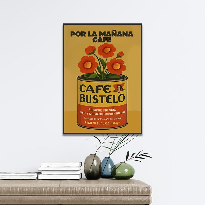 Pode incluir: Um cartaz vintage emoldurado para Cafe Bustelo, apresentando uma lata de caf&eacute; com o nome da marca e texto em espanhol. O cartaz tem um fundo amarelo com flores laranja e o texto "POR LA MA&Ntilde;ANA CAFE". O peso l&iacute;quido &eacute; de 283 gramas.