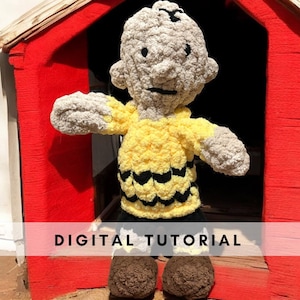 May include: A crocheted doll resembling a cartoon character, with a yellow top featuring black zigzags, black shorts, and brown shoes. The doll has a grey head and arms. The image includes the text "DIGITAL TUTORIAL".