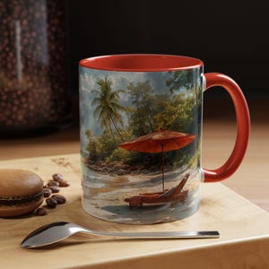 Puede incluir: Una taza de café roja y blanca con una escena de playa tropical. La taza presenta una palmera, una sombrilla y una tumbona en una playa de arena.