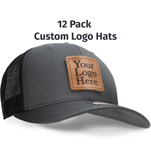 May include: A 12 pack of gray and black trucker hats with a brown leather patch that says "Your Logo Here".