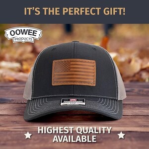 May include: A black and gray trucker hat with a brown leather American flag patch. The hat has a mesh back and a curved brim. The text "OOWEE PRODUCTS" is on the front of the hat.