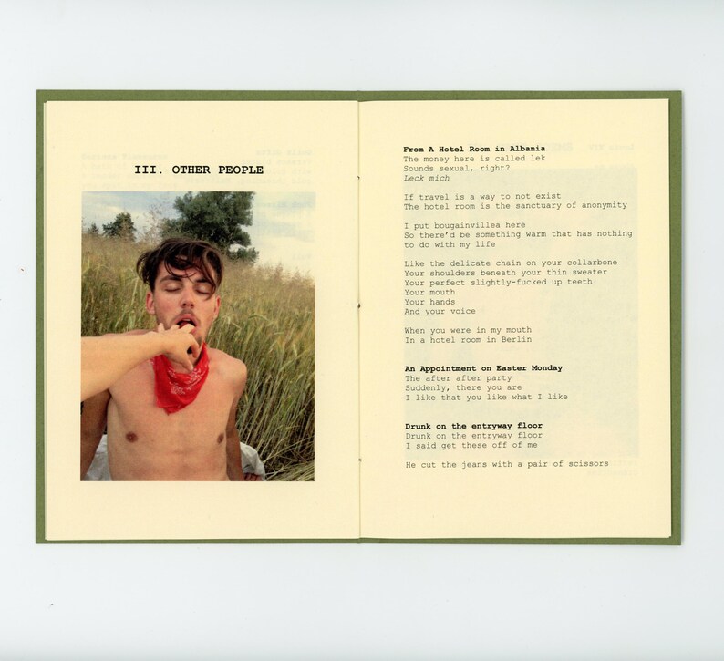 May include: A book with a green cover and white pages. The book is open to a page with a photo of a young man with a red bandana around his neck. The text on the page reads "III. OTHER PEOPLE" and "From A Hotel Room in Albania".