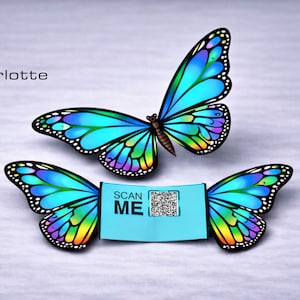 Könnte beinhalten: Zwei digital erstellte Schmetterlinge mit leuchtend blauen, grünen und gelben Flügeln. Einer der Schmetterlinge ist über dem anderen positioniert, mit einem hellblauen Etikett zwischen seinen Flügeln mit der Aufschrift "SCAN ME" und einem QR-Code. Das Bild enthält auch den Text "Plotterlotte Design".