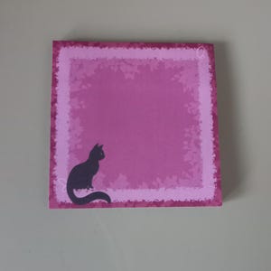 May include: A square, magenta sticky note pad featuring a black cat silhouette in the lower left corner. The pad has a lighter pink border with a textured design. The background is a solid magenta colour.