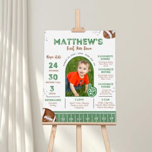 May include: A personalized first birthday sign featuring a photo of a baby in an orange shirt. The sign includes the baby's name, stats, favorite things, and a football theme. The baby is 30 inches tall and weighs 24 pounds.