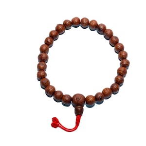 May include: A brown wooden bead bracelet with a red tassel. The bracelet is made of round, textured beads and is displayed against a white background. The beads are approximately 1.3 cm in diameter.
