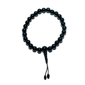 May include: A black beaded bracelet with a knotted tassel. The bracelet is made of round, polished beads and is displayed against a white background. The beads appear to be approximately 0.5 inches in diameter.