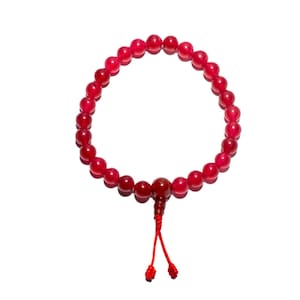 May include: A red beaded bracelet with a tassel. The bracelet is made of small, round, red beads strung together. A larger bead and tassel hang from the bracelet. The tassel is red and has two small knots at the end.
