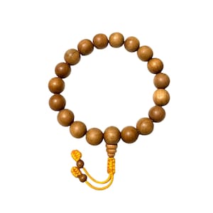 May include: A wooden bead bracelet with a yellow tassel. The bracelet features round, light brown beads strung together. The tassel is made of yellow thread and hangs from the bottom of the bracelet. The bracelet is displayed against a white background.
