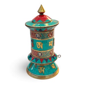 Könnte beinhalten: Eine türkisfarbene Gebetsmühle mit goldenen Akzenten und roten und blauen Details. Das Rad hat goldene Schriftzüge und eine konische Spitze. Der Sockel und die Oberseite sind mit komplizierten Mustern verziert. Die Gebetsmühle ist ein dekorativer Gegenstand.